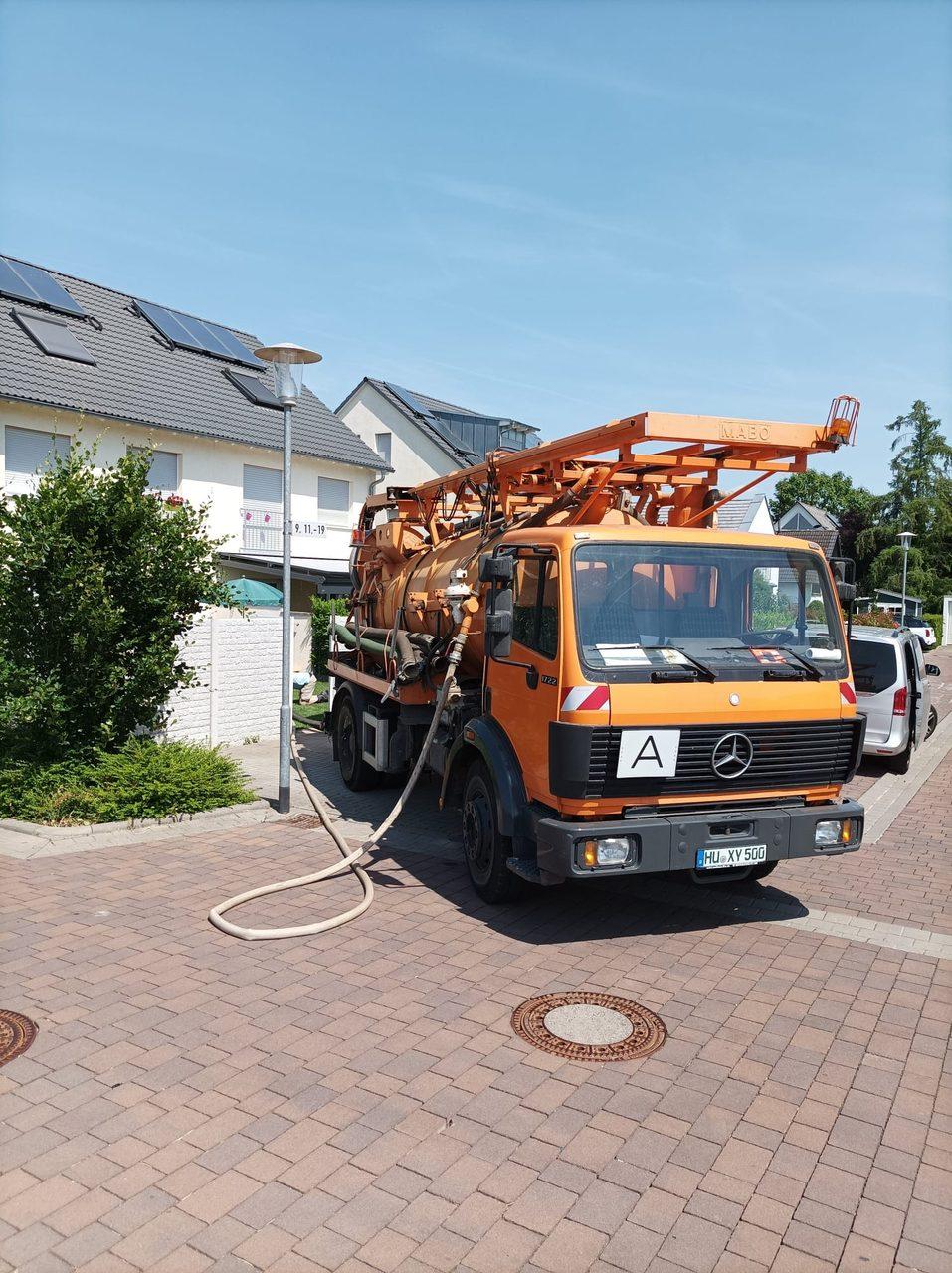 Orangefarbener Saugwagen von Rothhard Wassertechnik in einer Wohnstraße